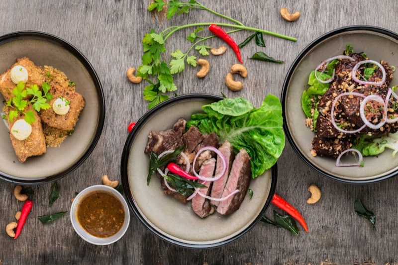 Three plated dishes on a wooden table